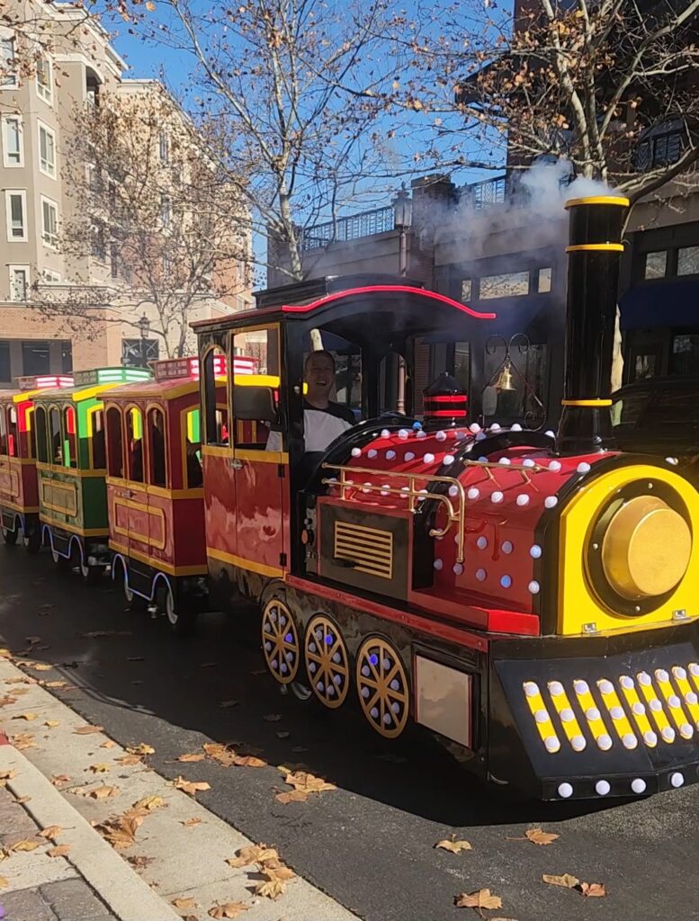All Aboard KC trackless train with the driver waving on a sunny Kansas City street