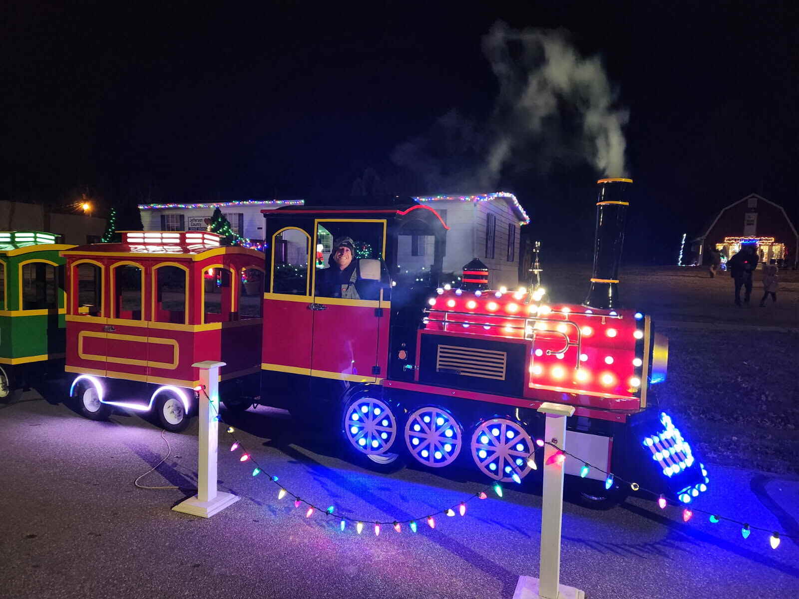 A uniformed conductor driving the All Aboard KC trackless train past holiday lights